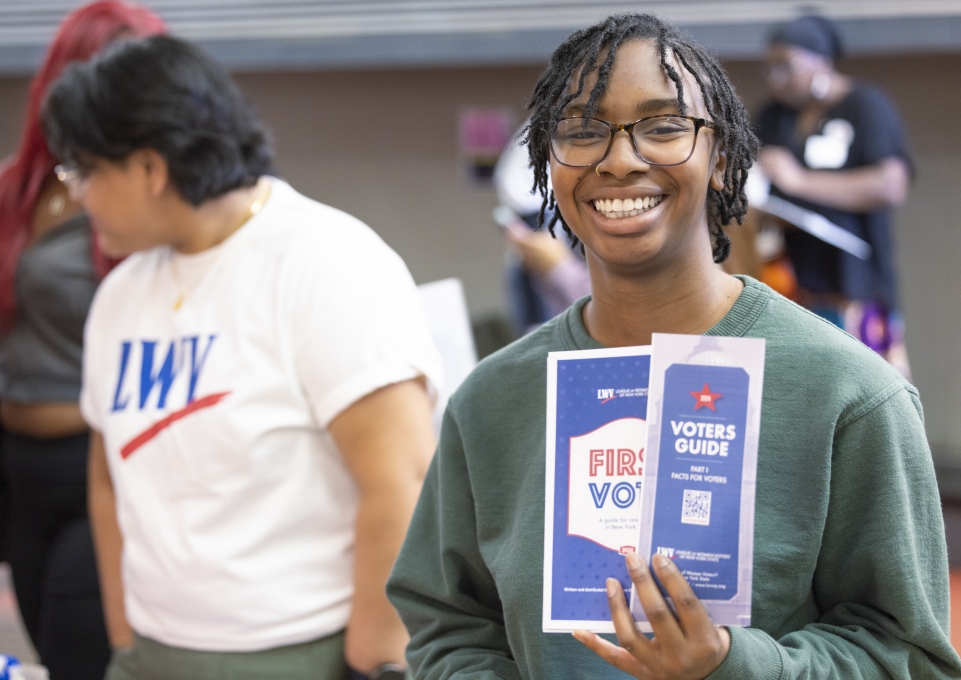Smiling student holding voter registration and voting guides
